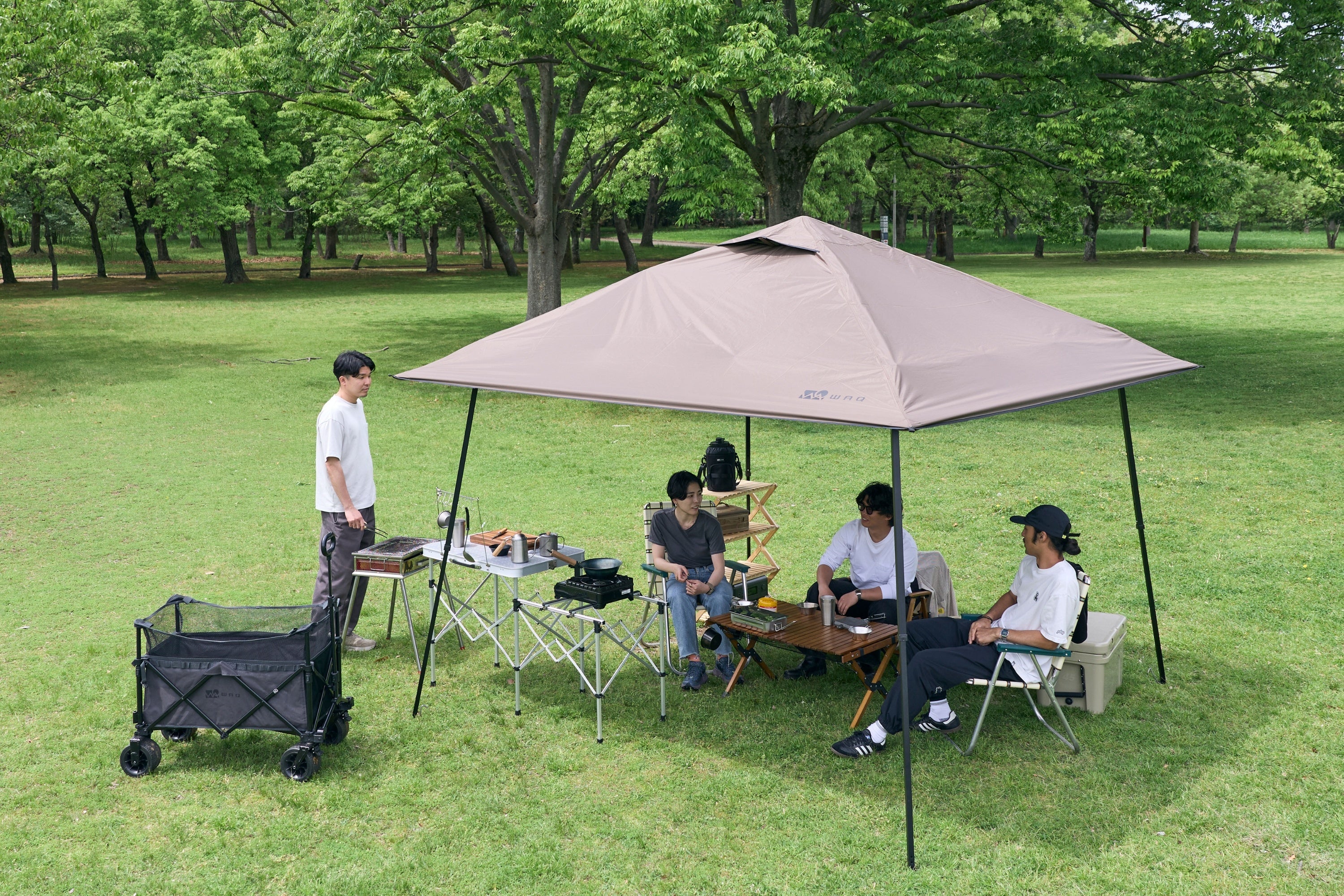 WAQ提供のEASE TARP 3.0、コヨーテ色の設営例。テーブル、チェア、ワゴン、人物は演出で本体の同梱品ではありません。
